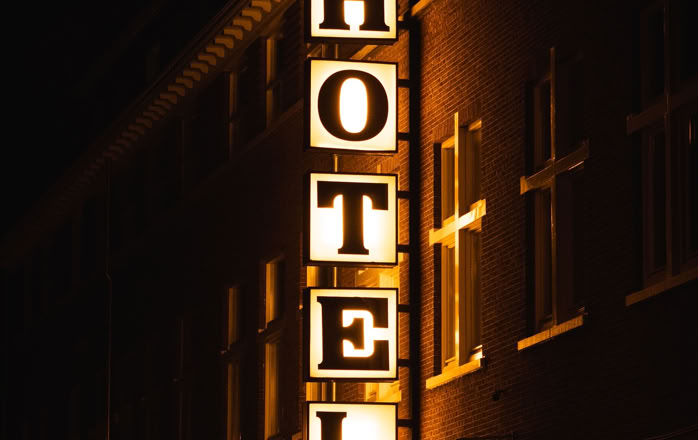 A bright hotel sign glowing on a building facade during nighttime.